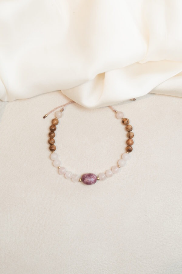 Lepidolith & Rosenquarz Armband Lepidolith - Selbstbestimmung • Wohlbefinden • Abgrenzung Lepidolith Eigenschaften: Mental: emotionale Balance, beruhigt den Geist, Stressbewältigung, bei Angst und Panikattacken, bringt Ruhe in die Gedanken, Klarheit und Selbstreflexion, Abgrenzung, filtert Umweltreize, hilft bei Hyperaktivität, Entspannung und Gelassenheit. Körper: Schmerzen, Gelenke, Hautreinigung, Schlaf, Verdauung, Ischias und Hormonsystem. Chakra: Drittes Auge, Kronenchakra Planet: Mond Element: Kosmos Sternzeichen: Jungfrau, Waage, Steinbock, Wassermann, Fische Mineralogische & historische Fakten: Lepidolith gehört zur Gruppe der Glimmerminerale und ist bekannt für seine zarte violette bis rosaviolette Farbe. Chemisch gesehen ist er ein Lithium-Aluminium-Silikat (K(Li,Al)3(Al,Si)4O10(F,OH)2). Die beruhigende Wirkung des Lepidoliths wird auch seiner chemischen Zusammensetzung zugeschrieben, denn Lithium ist bekannt für seine entspannenden Eigenschaften auf das Nervensystem. In der Geschichte wurde Lepidolith für seine Fähigkeit geschätzt, emotionale Blockaden zu lösen und innere Ruhe zu fördern. Er gilt als kraftvoller Begleiter für alle, die Klarheit und Gelassenheit suchen. Rosenquarz – Selbstliebe • Harmonie • Neubeginn Rosenquarz Eigenschaften: Mental: Liebe, Bedürfnisse erkennen, Trost, Selbstbewusstsein, Empathie, Einfühlungsvermögen, Harmonie, Verzeihung, Sinnlichkeit, Selbstliebe, Loslassen, Neubeginn und innere Ruhe. Körper: Blut, Kreislauf, Schlaf, Fruchtbarkeit, Herz, Kopfschmerzen, Gebärmutter, Hoden, Haut Chakra: Wurzelchakra und Herzchakra Planet: Venus Element: Wasser Sternzeichen: Widder, Stier, Zwillinge, Krebs, Waage, Schütze und Fische Details zum Schmuck: handgemachtes Armband • Größe verstellbar max. ø 90mm • Da es ein Naturprodukt ist, weichen Form und Farbe ab.