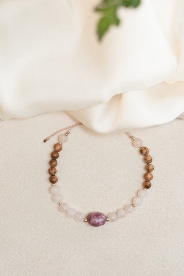 Lepidolith & Rosenquarz Armband Lepidolith - Selbstbestimmung • Wohlbefinden • Abgrenzung Lepidolith Eigenschaften: Mental: emotionale Balance, beruhigt den Geist, Stressbewältigung, bei Angst und Panikattacken, bringt Ruhe in die Gedanken, Klarheit und Selbstreflexion, Abgrenzung, filtert Umweltreize, hilft bei Hyperaktivität, Entspannung und Gelassenheit. Körper: Schmerzen, Gelenke, Hautreinigung, Schlaf, Verdauung, Ischias und Hormonsystem. Chakra: Drittes Auge, Kronenchakra Planet: Mond Element: Kosmos Sternzeichen: Jungfrau, Waage, Steinbock, Wassermann, Fische Mineralogische & historische Fakten: Lepidolith gehört zur Gruppe der Glimmerminerale und ist bekannt für seine zarte violette bis rosaviolette Farbe. Chemisch gesehen ist er ein Lithium-Aluminium-Silikat (K(Li,Al)3(Al,Si)4O10(F,OH)2). Die beruhigende Wirkung des Lepidoliths wird auch seiner chemischen Zusammensetzung zugeschrieben, denn Lithium ist bekannt für seine entspannenden Eigenschaften auf das Nervensystem. In der Geschichte wurde Lepidolith für seine Fähigkeit geschätzt, emotionale Blockaden zu lösen und innere Ruhe zu fördern. Er gilt als kraftvoller Begleiter für alle, die Klarheit und Gelassenheit suchen. Rosenquarz – Selbstliebe • Harmonie • Neubeginn Rosenquarz Eigenschaften: Mental: Liebe, Bedürfnisse erkennen, Trost, Selbstbewusstsein, Empathie, Einfühlungsvermögen, Harmonie, Verzeihung, Sinnlichkeit, Selbstliebe, Loslassen, Neubeginn und innere Ruhe. Körper: Blut, Kreislauf, Schlaf, Fruchtbarkeit, Herz, Kopfschmerzen, Gebärmutter, Hoden, Haut Chakra: Wurzelchakra und Herzchakra Planet: Venus Element: Wasser Sternzeichen: Widder, Stier, Zwillinge, Krebs, Waage, Schütze und Fische Details zum Schmuck: handgemachtes Armband • Größe verstellbar max. ø 90mm • Da es ein Naturprodukt ist, weichen Form und Farbe ab.