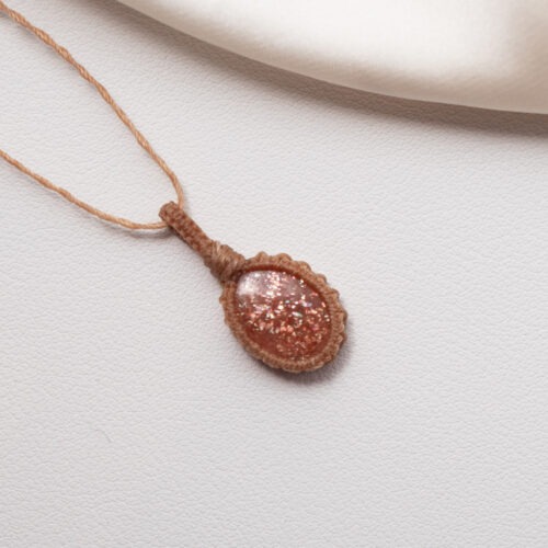 Sonne im Herzen – Makramee Ketten mit Sonnenstein  ☀️🧡 Sonne im Herzen steht für Wärme, Zuversicht und die Erinnerung an das eigene innere Licht. Diese Ketten vereinen sorgfältig ausgewählte Sonnensteine, die in feiner Makramee-Arbeit gefasst sind. Jeder Knoten hält den Stein achtsam und macht jede Kette zu einem Einzelstück. Der Sonnenstein wird traditionell mit Lebensfreude, Optimismus und innerer Stärke verbunden. Er unterstützt dabei, Vertrauen in sich selbst zu entwickeln, den eigenen Wert zu erkennen und dem Leben mit mehr Offenheit zu begegnen. Seine warme Ausstrahlung erinnert daran, dass Licht auch in stillen Momenten präsent sein darf. Die Makramee-Fassung unterstreicht diese Qualität. Sie hält den Stein nicht fest, sondern trägt ihn – flexibel, organisch und lebendig. Sonne im Herzen ist eine Kollektion für Menschen, die sich nach Wärme, Aufrichtung und einer leisen, stabilen Zuversicht sehnen. ✨ Themen: Mental: Optimismus, Lebensfreude, Urvertrauen, Selbstvertrauen, innerer Wachstum, Inspiration, Achtsamkeit, Annahme, innere Stärke Chakra: Sakralchakra Element: Feuer Sternzeichen: Löwe, Waage, Jungfrau, Widder 🗿 Mineralogische & historische Fakten: Der Sonnenstein gehört zur Feldspatgruppe und zeigt einen typischen goldrötlichen Glanz (Aventureszenz), der durch Einschlüsse wie Hämatit oder Goethit entsteht. Chemisch handelt es sich meist um einen Oligoklas oder Labradorit. Bereits in der Antike wurde er als Stein des Lichtes und der Götter verehrt. Die Wikinger nutzten vermutlich transparente Varianten als Navigationshilfe – um auch bei bedecktem Himmel die Sonne zu orten. In der spirituellen Arbeit steht der Sonnenstein für Freude, Leichtigkeit und das innere Strahlen. Er erinnert daran, dass selbst hinter dunklen Wolken immer die Sonne scheint.