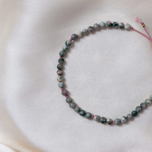 Essenz – Pektolith & Heliotrop Armband Dieses Armband vereint Pektolith mit Heliotrop in einer besonderen Farbkomposition aus Grün- und Rosétönen. Pektolith bildet das Herzstück des Designs und steht für Klarheit, Wahrhaftigkeit und den Zugang zur eigenen inneren Essenz. Er begleitet dabei, bei sich zu bleiben, innere Prozesse bewusst wahrzunehmen und dem Wesentlichen Raum zu geben. Der ergänzende Heliotrop bringt eine erdende, stabilisierende Qualität in das Armband. Er wird traditionell mit Standfestigkeit, Abgrenzung und emotionalem Ausgleich in Verbindung gebracht. In dieser Farbausprägung wirkt er weniger streng und fügt sich ruhig und harmonisch in die Gesamtwirkung ein. Heliotrop ist im Handel unter verschiedenen Namen und Farbvarianten bekannt. Unabhängig davon gehört er mineralogisch zur Gruppe der Chalcedone und wird hier bewusst als Heliotrop geführt. Gemeinsam schaffen Pektolith und Heliotrop eine ausgewogene Verbindung aus Klarheit und Erdung. Essenz ist ein Armband für Menschen, die Tiefe schätzen, bewusst fühlen und innere Ordnung nicht suchen, sondern leben. Pektolith Innere Klarheit Wahrhaftigkeit & Selbstausdruck Emotionale Zentrierung Heliotrop Erdung & Stabilität Abgrenzung Innere Ruhe ☝🏼 Details zum Edelstein Schmuck Naturstein – daher kann der Edelstein von den Bildern abweichen. Größe mit Makramee Schiebeknoten verstellbar. ca. 15 – 24 cm Länge weitere Elemente: Edelstahl vergoldet. mit Liebe und Intuition handgemacht 💜