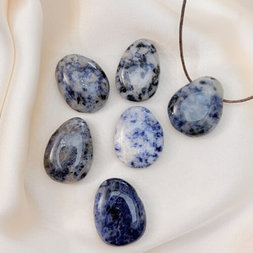 Sodalith – Der Edelstein der Wahrheit und Befreiung 💙✨ Ich löse, was nicht zu mir gehört, und öffne mich für meine Wahrheit. Sodalith ist ein Stein der Befreiung. Er hilft dir, blockierte Gefühle zu lösen und das loszulassen, was nicht zu deiner Identität gehört. Seine tiefblaue, klare Energie verbindet Bewusstsein und Unterbewusstsein, schärft die Wahrnehmung und schenkt Mut, deine Wahrheit zu leben. Gleichzeitig stärkt er Motivation, Ausdauer und Durchsetzungskraft – ideal, wenn du mit idealistischem Herz („Weltverbesserer“) deine Werte in die Welt bringen willst. Er macht nachdenklich auf die gute Art: ehrlich, klar, zentriert. ✨ Themen Sodalith Mental: Wahrnehmung schärfen, Blockaden lösen, Gefühle befreien, Identität klären, verbindet Bewusstsein & Unterbewusstsein, Motivation, Idealismus, Weltverbesserer-Energie, Wahrheit, Ausdauer, Mut, Nachdenklichkeit, Durchsetzungskraft Chakra: Halschakra, Drittes Auge Planet: Jupiter Element: Wasser Sternzeichen: Schütze, Jungfrau, Krebs 🗿 Mineralogische & historische Fakten Sodalith ist ein Natrium-Aluminium-Silikat aus der Feldspatvertreter-Gruppe. Typisch sind tiefblaue Töne mit weißen Calcit-Adern – wie Wolken am Himmel. Er wurde im 19. Jh. in Grönland beschrieben und wurde rasch als Schmuck- und Heilstein beliebt. Spirituell steht er für Wahrheit, geistige Freiheit und innere Stärke. 🗿 Details  Die Anhänger sind ca. 30 x 40 mm groß Jeder Stein wird bewusst ausgewählt und naturbelassen verarbeitet. Durch die gebohrte Form lassen sich die Alltagsanker direkt an einem zarten Band tragen oder individuell kombinieren. Diese Anhänger sind keine Unikate im klassischen Sinn, sondern bewusst einfach gehaltene Begleiter. Sie stehen nicht im Vordergrund, sondern wirken still im Hintergrund. Als Edelstein für zwischendurch, als Geschenk oder als persönlicher Alltagsanker.