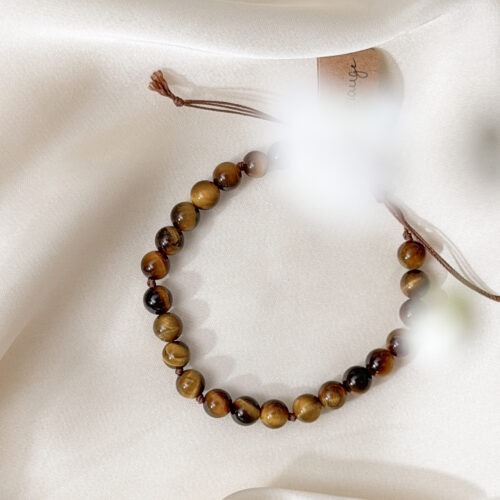 Tigerauge – Der Edelstein der inneren Stärke und Klarheit 🐅 Ich stehe zu mir. Kraftvoll, klar und beschützt. Tigerauge ist dein energetischer Begleiter, wenn du dich zentrieren und mutig durchs Leben gehen möchtest. Wie das Licht, das über seine goldbraune Oberfläche tanzt, bringt er Klarheit in Gedanken, Entscheidungen und dein Selbstbild. Er stärkt das Vertrauen in dich selbst, fördert deine Wachsamkeit und hilft dir dabei, in turbulenten Phasen Ruhe zu bewahren. Tigerauge schenkt dir Erdung und Entschlossenheit – und erinnert dich daran, dass du sicher bist, wenn du in dir selbst verankert bist. ✨ Themen Tigerauge Mental: Schutz, Ich-Stärkung, Grenzen setzen, Wachsamkeit, Stimmung, Entschlossenheit, Intuition, Geborgenheit, innere Kraft, Selbstbewusstsein, Depressionen Körper: Motorik, Magen, Darm, Knochen, Atemwege, Kopf Chakra: Solarplexus, Wurzelchakra Planet: Sonne Element: Feuer Sternzeichen: Jungfrau, Zwillinge, Löwe, Widder, Stier, Skorpion, Schütze 🗿 Mineralogische & historische Fakten: Tigerauge ist eine goldbraune, faserige Variante des Quarzes, die durch Verwitterung von Krokydolith entsteht. Die schimmernde Lichtreflexion, auch „Chatoyance“ genannt, erinnert an das Auge einer Raubkatze und verleiht dem Stein seinen Namen. Schon in der Antike galt Tigerauge als Schutzstein gegen Flüche und den “bösen Blick”. In Afrika, Asien und im alten Rom trug man ihn als Talisman für Mut, Kraft und Weitblick. Heute ist er besonders in Phasen des Umbruchs und der Selbstfindung beliebt – als Stein, der dich erdet und stärkt. Wusstest du schon? Tigerauge wurde von Kriegern getragen, um Mut und strategische Klarheit im Kampf zu bewahren. In der Meditation soll er helfen, das „dritte Auge“ mit dem Bauchgefühl zu verbinden – für geerdete Intuition. ☝🏼 Details zum Edelstein Schmuck Naturstein – daher kann der Edelstein von den Bildern abweichen. Größe mit Makramee Schiebeknoten verstellbar. 15 – 24 cm Länge 6 mm Edelsteinperlen. weitere Elemente: Edelstahl vergoldet. mit Liebe und Intuition handgemacht 