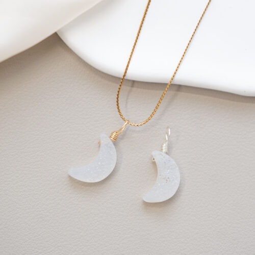 Druzy Achat – Dein inneres Leuchten & Schutz 💎✨ Affirmation: „Ich erkenne das wertvolle Strahlen in meinem Inneren.“ Der Druzy Achat ist ein faszinierendes Wunder der Natur. Während seine Basis für Schutz und tiefe Erdung steht, offenbart er in seinem Inneren eine Schicht aus unzähligen, winzigen Kristallen. Dieses Funkeln erinnert uns daran, dass wir – egal was im Außen passiert – ein eigenes, unerschütterliches Licht in uns tragen. Er ist ein Stein der Transformation, der dir hilft, deine innere Stärke zu finden und deine verborgenen Talente mit Selbstvertrauen nach außen zu tragen. ✨ Inspirationen Schwarz (Black is shining): Fokus, Schutz vor negativen Energien und Erdung. Rosa (Soft Glow): Selbstliebe, Herzöffnung und sanfte emotionale Balance. Weiß (Pure Light): Klarheit, Reinigung und ein frischer Neuanfang. Allgemeine Themen: Inneres Strahlen, Selbstvertrauen, Transformation, Individualität, Schutzraum, Schutz, Sicherheit, Geborgenheit, Problemlösung, Stabilität, Verbindung zum Kollektiv, Kollektivbewusstsein. Element. Erde und Wasser. Sternzeichen: Stier, Steinbock, Fische, Skorpion 🗿 Mineralogie: Als „Druzy“ bezeichnet man eine kristalline Schicht auf der Oberfläche oder in Hohlräumen eines Minerals. Beim Druzy Achat handelt es sich um Millionen kleiner Quarzkristalle, die über Jahrtausende gewachsen sind. Diese Struktur bricht das Licht in alle Richtungen und sorgt für das charakteristische, sternenstaubähnliche Glitzern. 🔮 Mythos & Geschichte: Drusen gelten seit jeher als Symbole für das „Licht im Verborgenen“. Sie stehen für die Entdeckung der eigenen Schätze und die Fähigkeit, selbst in festgefahrenen Situationen einen funkelnden Ausweg oder eine neue Perspektive zu finden. Er wird oft als Stein für Individualisten geschätzt, die ihre Einzigartigkeit feiern. 🪄 Ganz ohne Hokuspokus: Das dezente Glitzern der Druse zieht die Aufmerksamkeit sanft auf sich und dient als hervorragender visueller Anker für Achtsamkeitsübungen. Er erinnert dich im hektischen Alltag daran, kurz innezuhalten und dich auf deine eigene Kraft zu fokussieren. Bitte beachte: Edelsteine sind kein Ersatz für medizinische Behandlungen oder professionelle Therapie. ☝🏼 Details zum Edelstein Schmuck Handarbeit: Mit Achtsamkeit und Intuition handgefertigtes Schmuckstück. Größe: Der Anhänger in eleganter Pendelform hat die Maße von ca. 18 x 8 mm Material: Echter Naturstein und Kupferdraht (14k vergoldet). Unikat-Garantie: Da es sich um echte Natursteine handelt, ist jedes Schmuckstück ein Einzelstück. Besonders die Kristallstruktur der Druse ist bei jedem Stein einzigartig. Lieferumfang nur der Anhänger