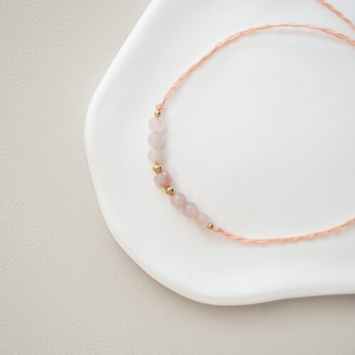 Seelenfeuer – Zartes Armband mit Rubin & Rosenquarz ❤️🌸 Affirmation: „Ich nehme mich liebevoll so an, wie ich bin, während das Feuer meiner eigenen Kraft und Lebensfreude tief in mir brennt.“ Das zarte Armband „Seelenfeuer“ vereint zwei kraftvolle Energien des Herzens auf eine ganz subtile, elegante Weise. Es ist ein stiller Begleiter für deinen Alltag, der Gegensätze harmonisch miteinander verbindet und dich daran erinnert, dass Kraft und Sanftmut kein Widerspruch sind. In diesem Schmuckstück verschmelzen die feurige Urkraft des Rubins und die weiche Geborgenheit des Rosenquarzes. Während der Rosenquarz dich sanft einhüllt, dir den Raum für tiefe Selbstliebe schenkt und dich lehrt, auf deine eigenen Bedürfnisse zu hören, entfacht der Rubin dein inneres Feuer. Er bringt Lebensenergie, Leidenschaft und den Mut mit sich, deine Wahrheit im Außen zu leben. Zusammen bilden sie das Seelenfeuer: Sie unterstützen dich dabei, absolut weich und liebevoll mit dir selbst zu sein, während du gleichzeitig unerschütterlich stark für dich einstehst. ✨ Tiefe Zuordnungen der Edelsteine: Rosenquarz: Mental: Liebe, Trost, Empathie, Einfühlungsvermögen, Verzeihung, Sinnlichkeit, Selbstbewusstsein, Loslassen, Neubeginn, innere Ruhe Chakra: Wurzelchakra, Herzchakra Element: Wasser Sternzeichen: Widder, Stier, Zwillinge, Krebs, Waage, Schütze, Fische Rubin: Mental: Sexualität, Emotionen, Selbstverwirklichung, Intuition, Schutz Chakra: Wurzelchakra, Herzchakra Element: Feuer Sternzeichen: Krebs, Widder, Löwe, Jungfrau, Skorpion, Schütze 🗿 Mineralogie: Fundort: Indien / Madagaskar. Fakten: Der Rubin ist die rote Varietät des Minerals Korund (Aluminiumoxid) und gehört mit einer spektakulären Mohshärte von 9 zu den härtesten Edelsteinen der Erde. Der Rosenquarz ist eine weichere Quarz-Varietät (Härte 7), dessen zartes Rosa durch feinste Einschlüsse von Titan- oder Mangan-Dendriten entsteht. 🔮 Mythos & Geschichte: In alten Kulturen wurde der Rubin als „Stein der Könige“ verehrt und galt als Symbol für unerschütterliche Lebenskraft und das innere Feuer. Der Rosenquarz wird hingegen seit der Antike als der klassische Stein der Liebe, des Friedens und der emotionalen Harmonie geschätzt. Zusammen bilden sie ein zeitloses Duo aus Feuer und Sanftmut.